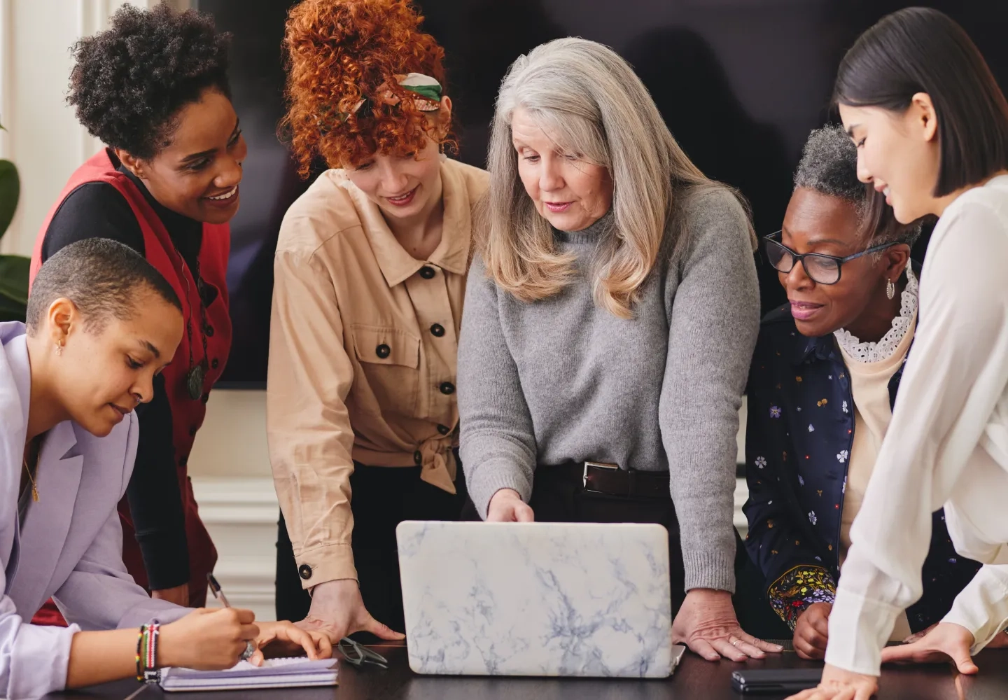 Group of professional women gathered around a laptop